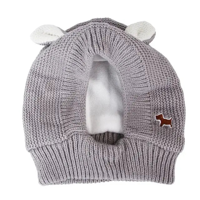 Un bonnet tricoté gris avec un pompon blanc ; idéal pour les oreilles sensibles des chiens dans les environnements bruyants